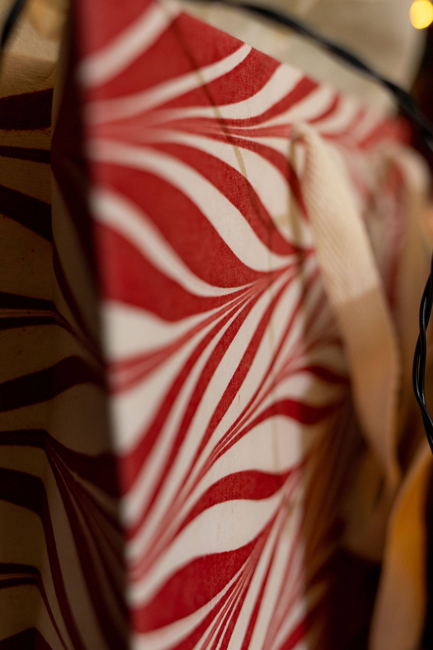 Alt Tag: Hand marbled Christmas gift bag with cotton rope handles from stationery store collection, featuring red swirl design.