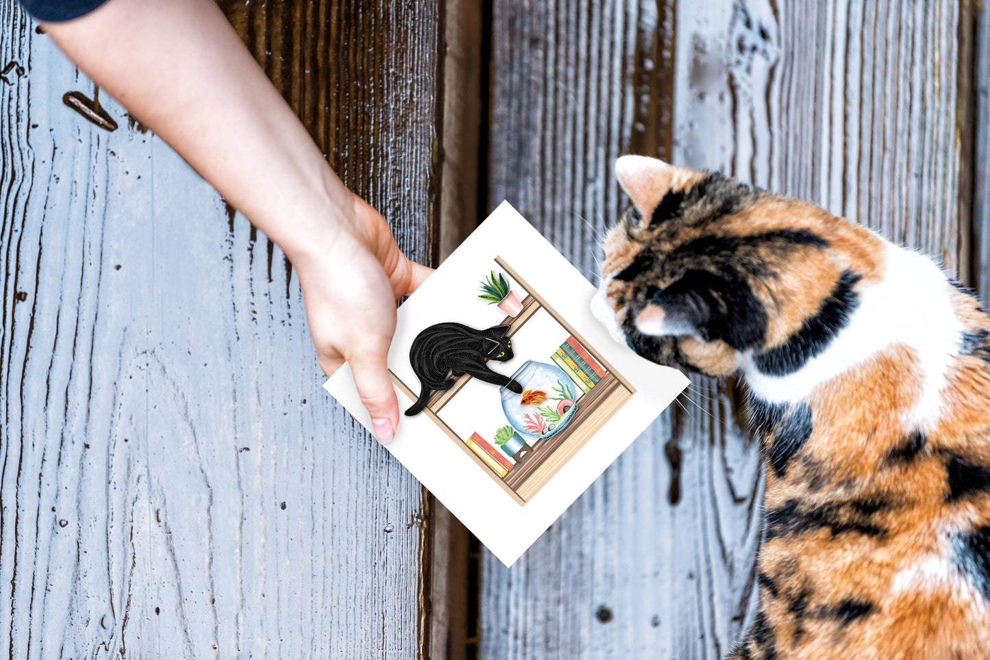 Person holding Quilled Mischievous Cat Greeting Card with cat illustration near curious cat, perfect for stationery store joy.