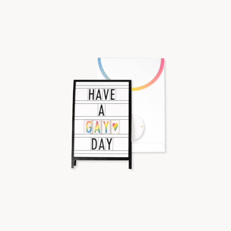 Marquee Pride Pop-Up Card with 'Have a Gay Day' message, featuring rainbow design on envelope from stationery store.