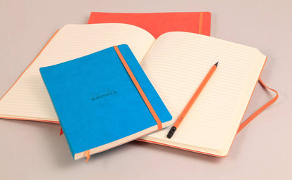 Rhodiarama Softcover Journal A5 with lined paper and elastic closure, available at stationery store, featuring a blue cover and orange accents.