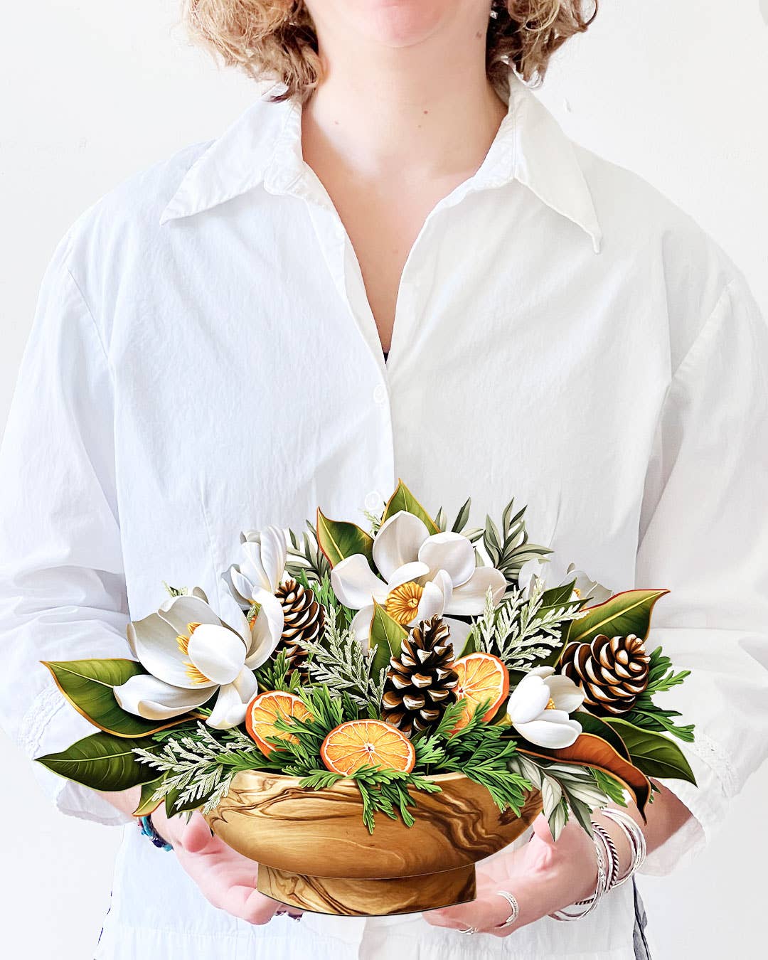 Winter Magnolia Pop-up Greeting Card with magnolias, orange slices, pine cones in a wooden bowl, available at stationery store.