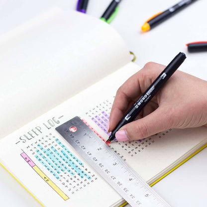 A person using a black MONO Edge Highlighter to decorate a sleep log in a planner with a metal ruler, ideal for stationery store supplies.