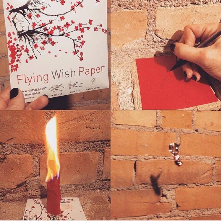 Flying wish paper mini kit with red stationery, writing note, and burning paper against a brick wall, from a stationery store.