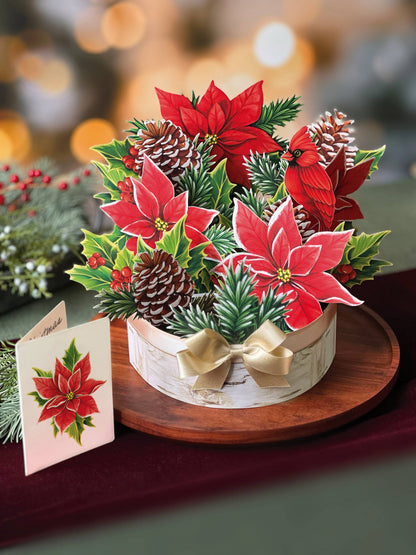 Birch Poinsettia Pop-up Greeting Card with paper base, note card, pinecones, and poinsettia in birch log, available at stationery store.