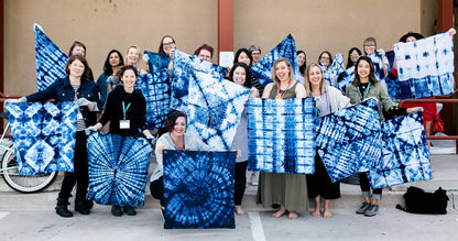 Group showcasing fabrics dyed with Indigo Tie Dye Kit, featuring unique patterns and designs at a stationery store workshop.