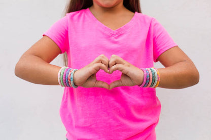 Child wearing colorful Rollies® bracelets forming a heart shape, perfect for kids' stationery store jewelry collection.