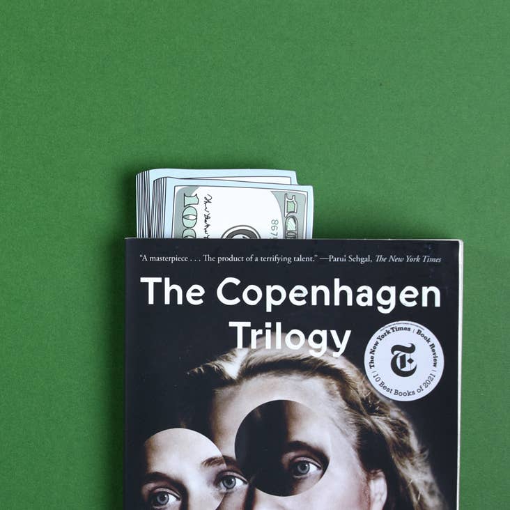 Stack of Cash die-cut bookmark sticking out from 'The Copenhagen Trilogy' book, available at our stationery store.