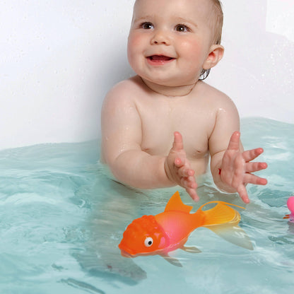 Happy baby playing with Koi Toy Light-Up Goldfish in bath; perfect for fun, glowing bath time; available at stationery stores; BPA-free.