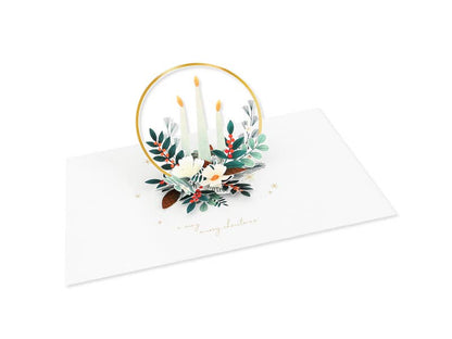 Christmas Candles Pop-Up Card with laser-cut candles and winter sprigs, featuring a golden hoop. Available at stationery store.