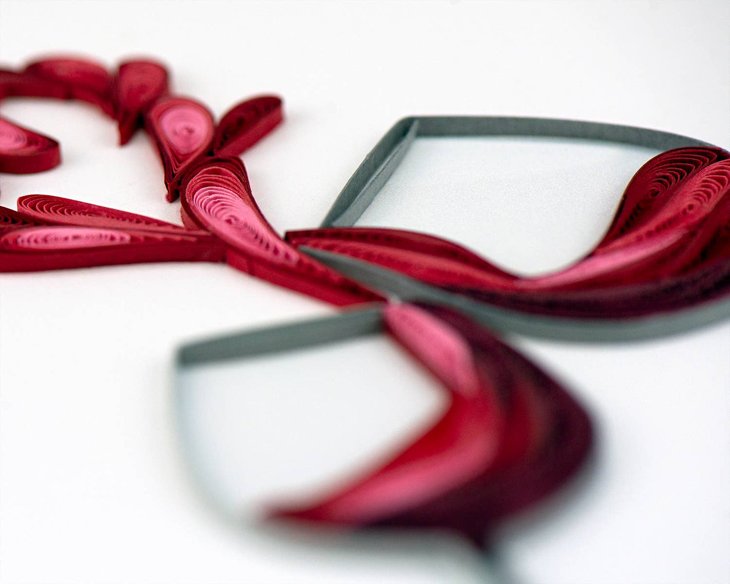 Quilled wine glasses forming heart on 'A Toast to Love' card from a stationery store, symbolizing romance and affection.