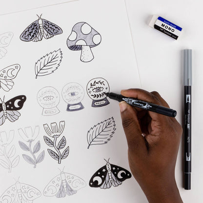 Person using Tombow Drawing Set from stationery store, creating intricate doodles with Fudenosuke brush pen on white paper.