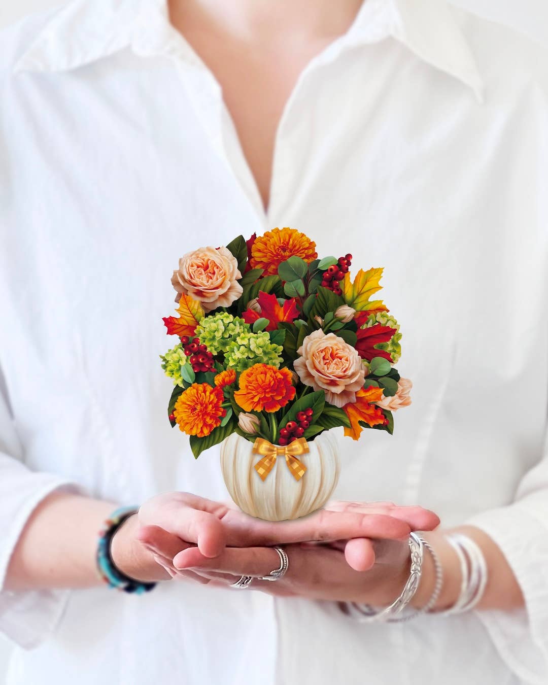 Hands holding a Mini Pumpkin Spice Pop-up Greeting Card with vibrant flowers, perfect for a stationery store gift.