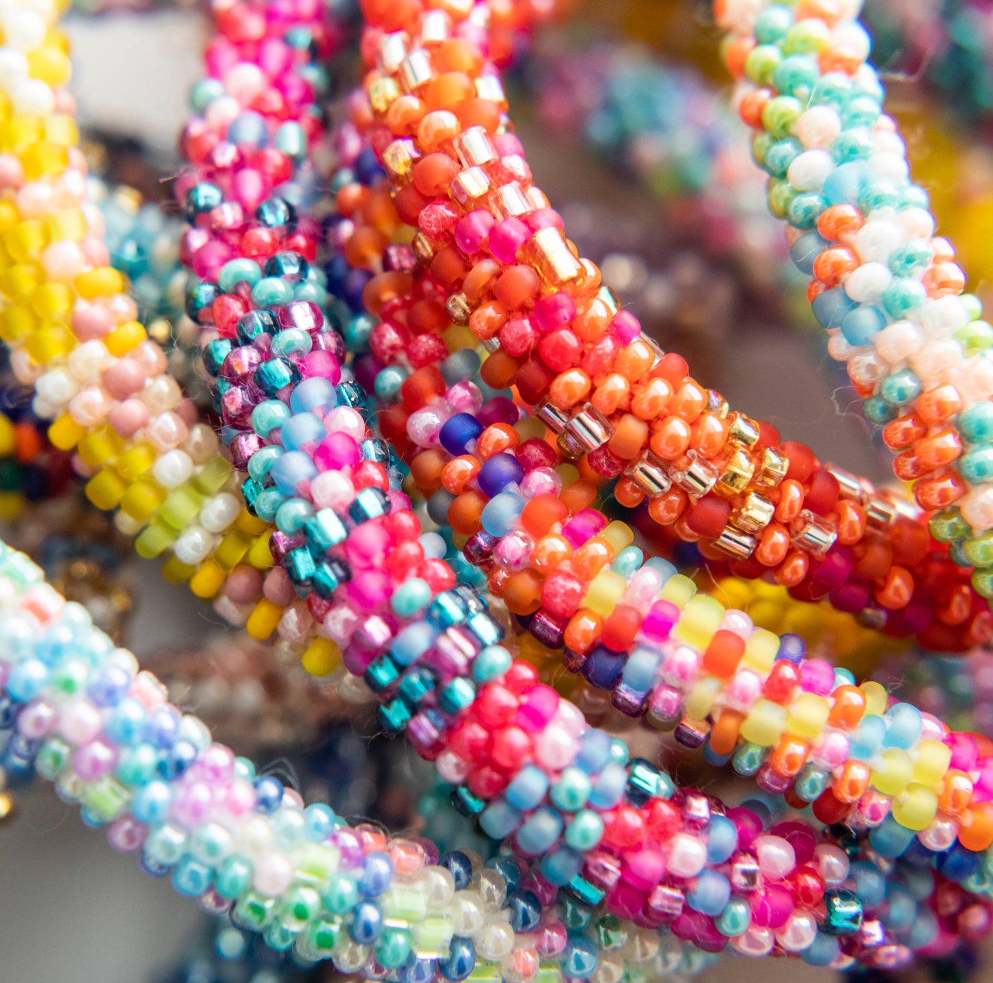 Colorful Rollies® for Kids bracelets, featuring vibrant speckled beads in blues, purples, reds, and yellows. Perfect for any outfit. Stationery store.