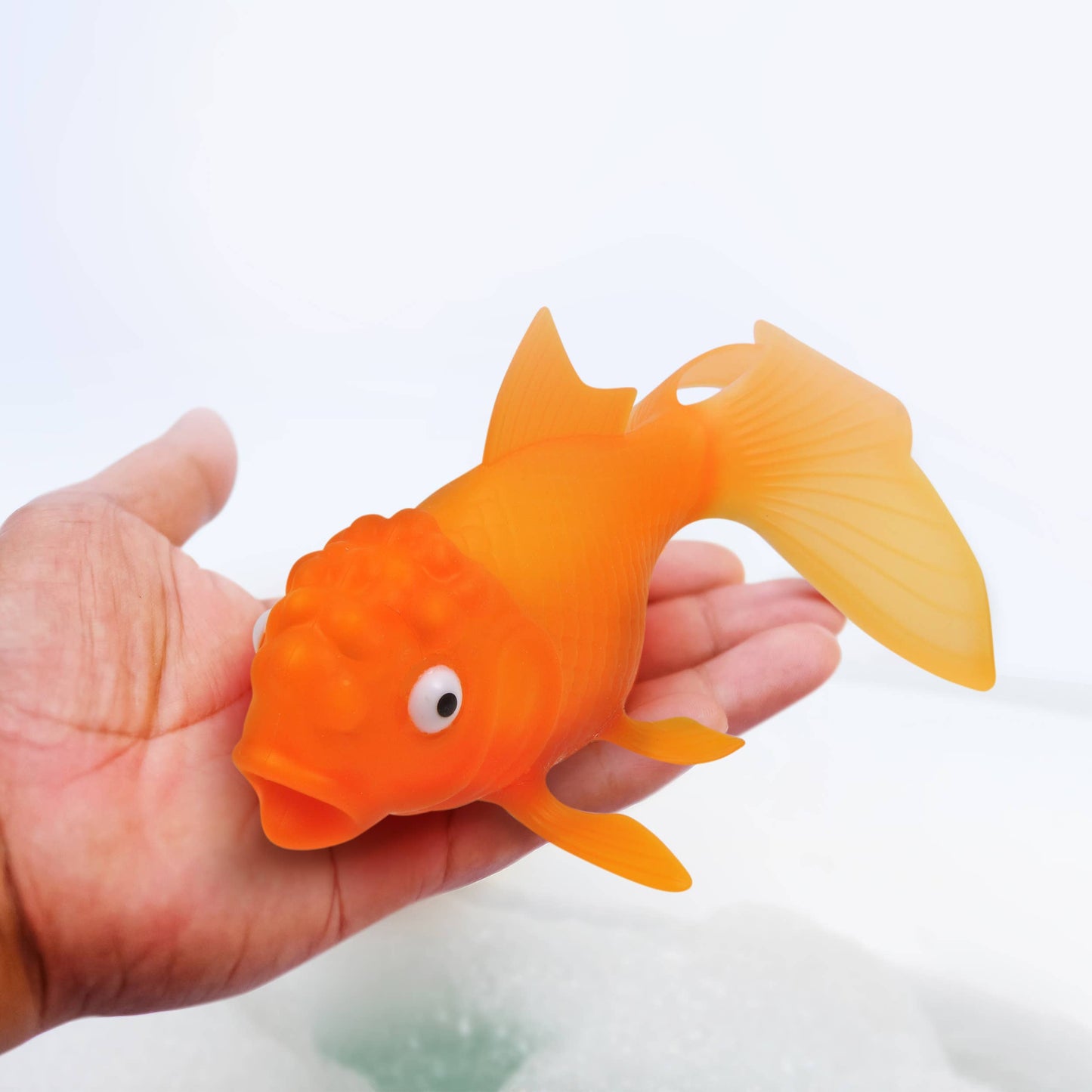 Hand holding Koi Toy Light-Up Goldfish bath & pool toy, BPA-free silicone, colorful glow, perfect for stationery store displays