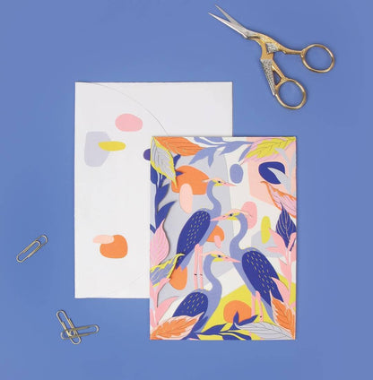 No. 37 Herons Die-Cut Card on blue surface with envelope, gold foil accents, stationery scissors, and paperclips, ideal for stationery store.