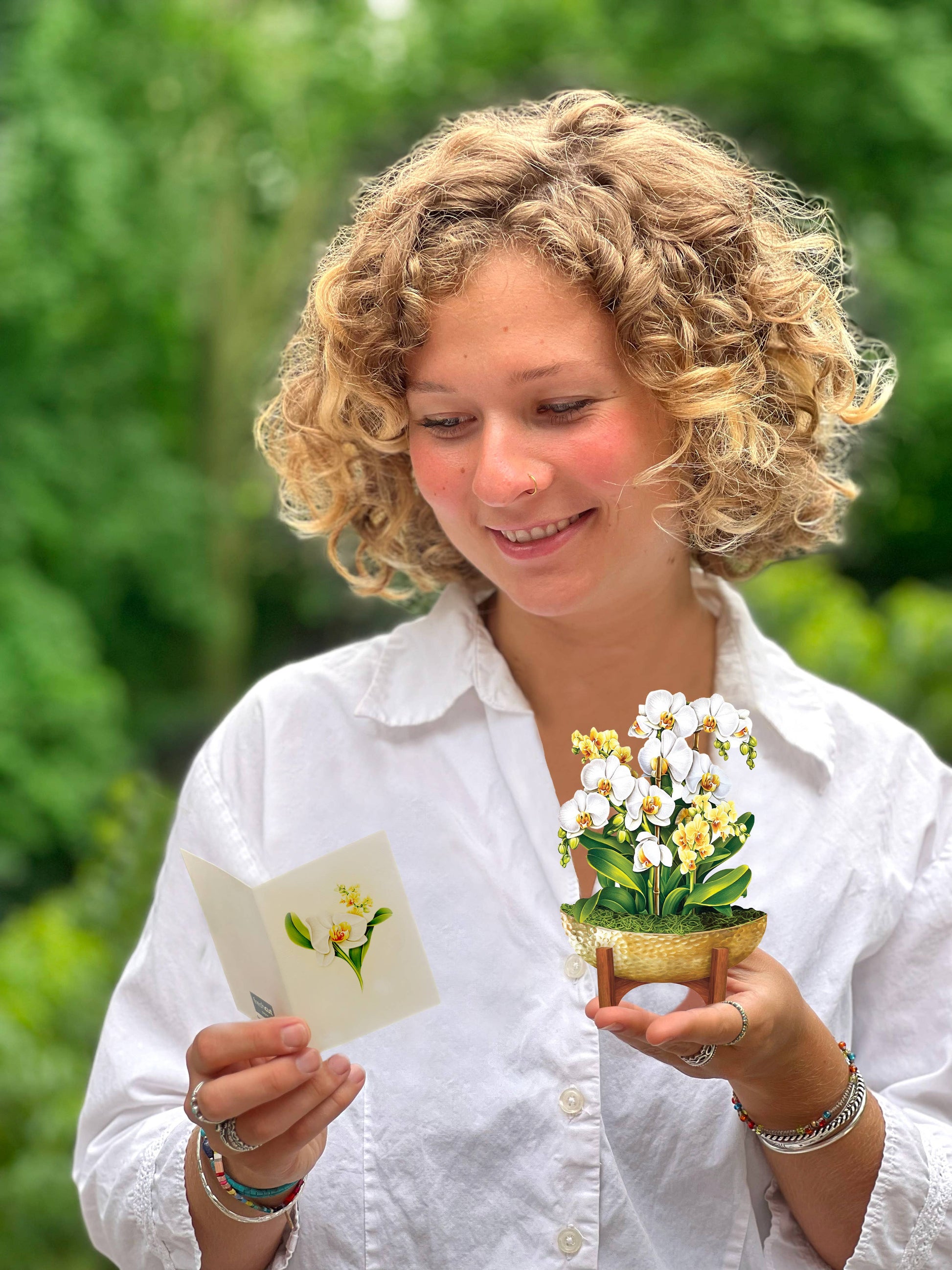 Woman holding Mini Serenity Orchid pop-up greeting card and note, available at stationery store, symbolizing hope and harmony.