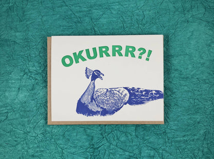 A2 greeting card featuring 'Okurrr' with a blue peacock design by Guttersnipe Press, available at stationery store.