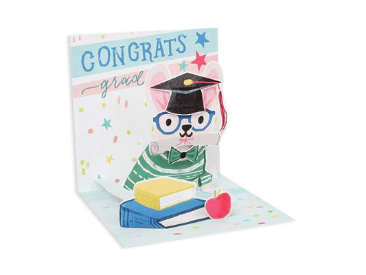 Dog Graduate Pop-Up Card with colorful artwork and glitter, available at a stationery store. Features "Congrats Grad" message.