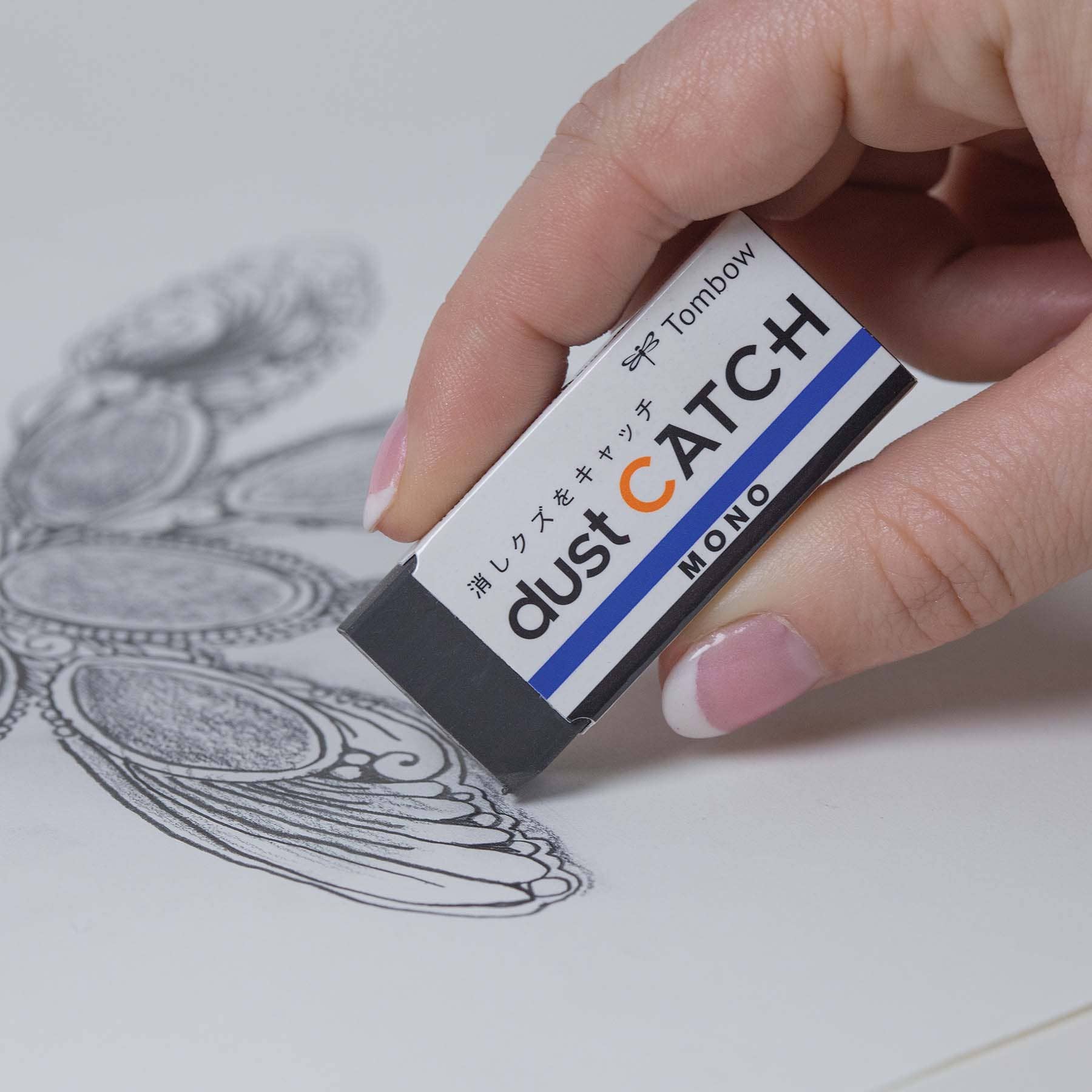 Person using MONO Dust Catch Eraser on artwork, preventing residue; ideal for stationery stores.