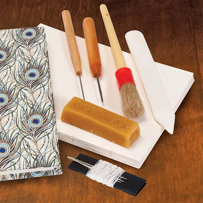 Lineco Bookbinding Tool Kit available at stationery store, includes tools like beeswax, brush, paper folder, and needle for custom bookbinding.