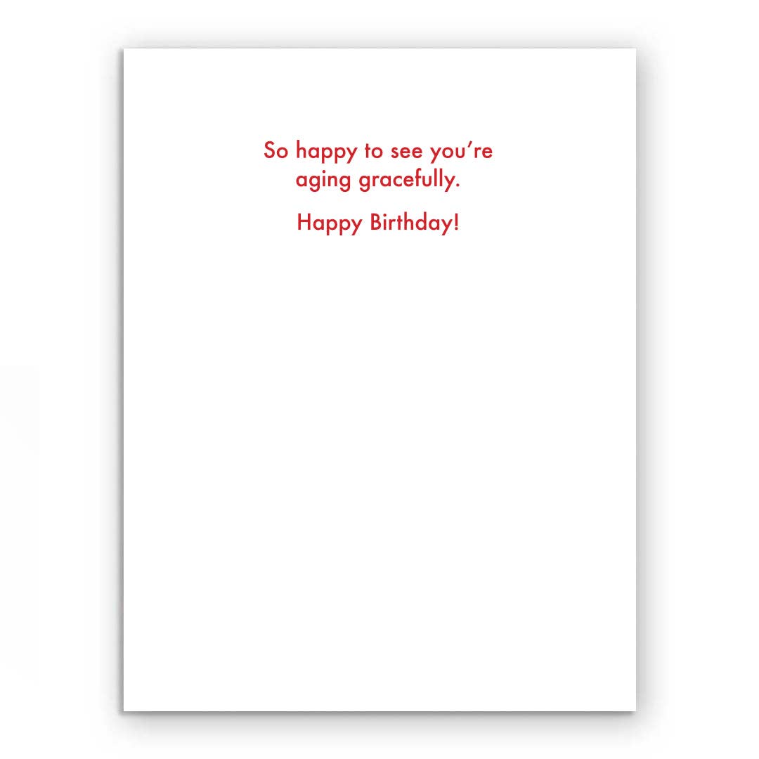 Aging Gracefully Doll Birthday Card with red text: 'So happy to see you're aging gracefully. Happy Birthday!' Ideal for stationery stores.