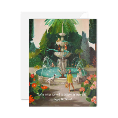 Birthday card featuring a whimsical scene at a mermaid public fountain, blank inside, available at stationery stores.