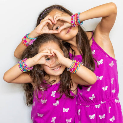 Two girls wearing vibrant Rollies® for Kids bracelets from the Kids Party Pack, displaying colorful fashion accessory from a stationery store.