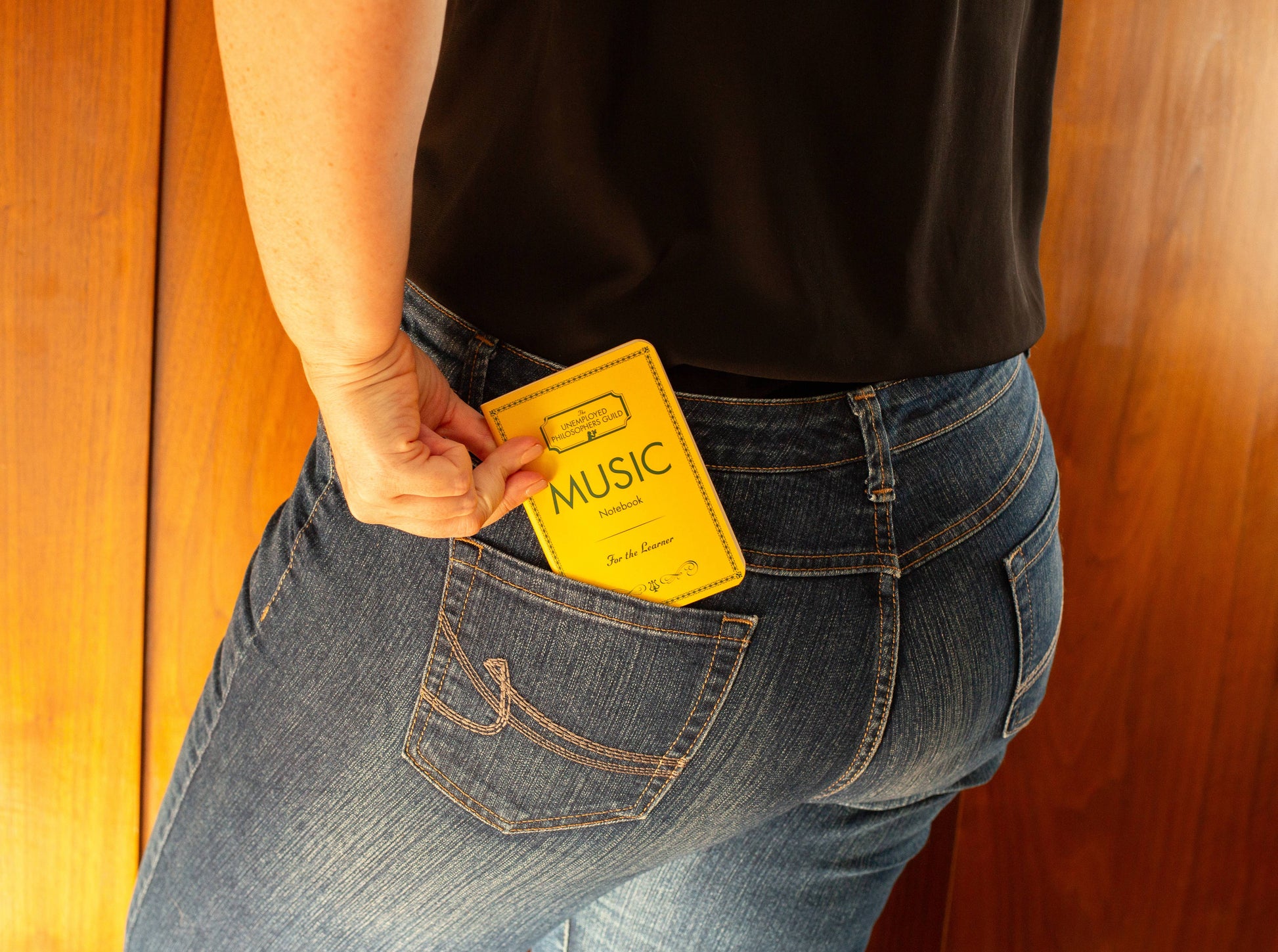 Music Notebook pocket-sized 3x5 inches being placed in a jeans pocket, perfect for music notes. Available at stationery stores.