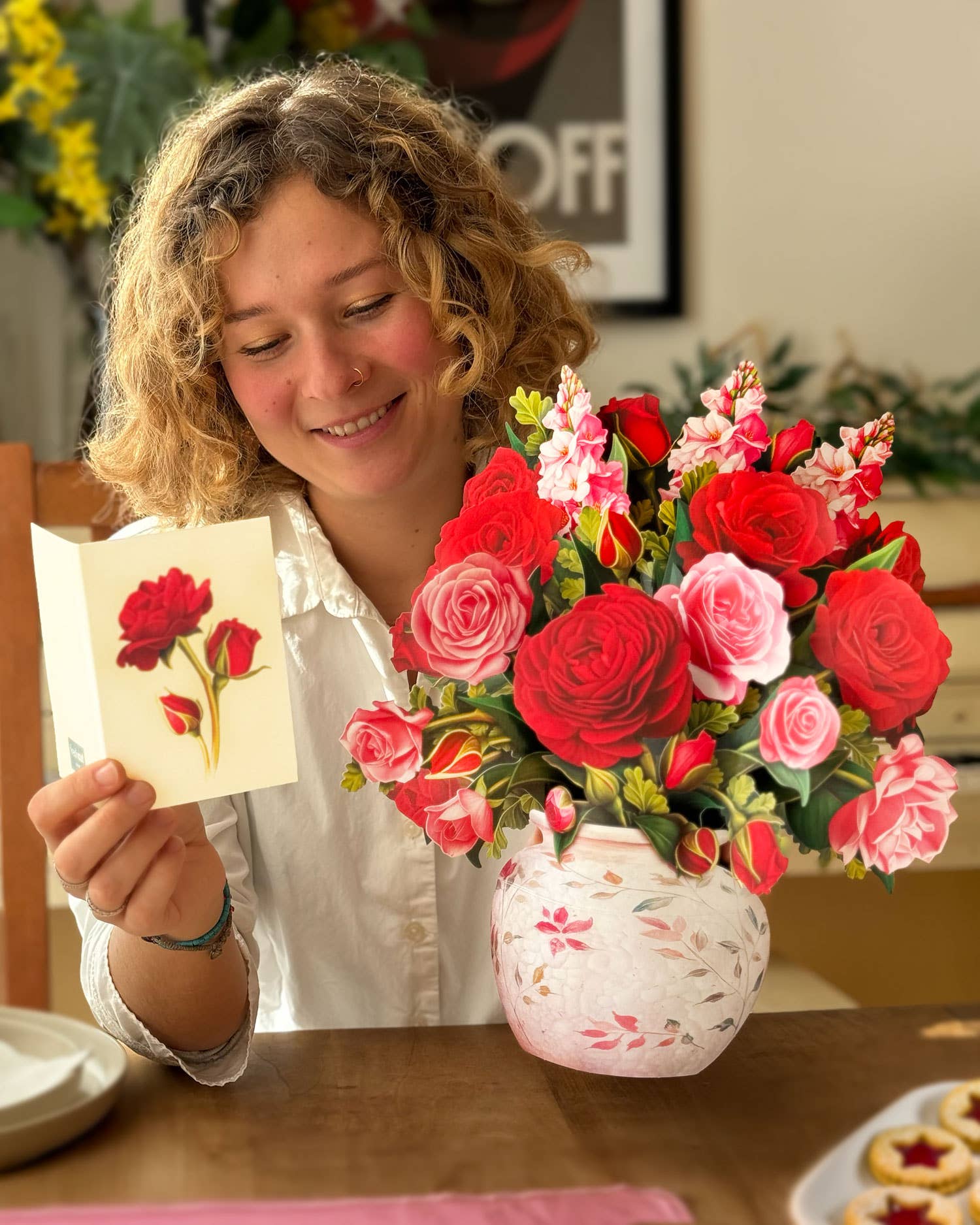 Woman admiring Blooming Roses Pop Up Greeting Card with a floral vase, perfect stationery store find.