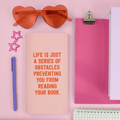 Avid Reader Traveler Notebook with motivational quote, surrounded by stationery supplies and heart-shaped glasses, available at stationery store.