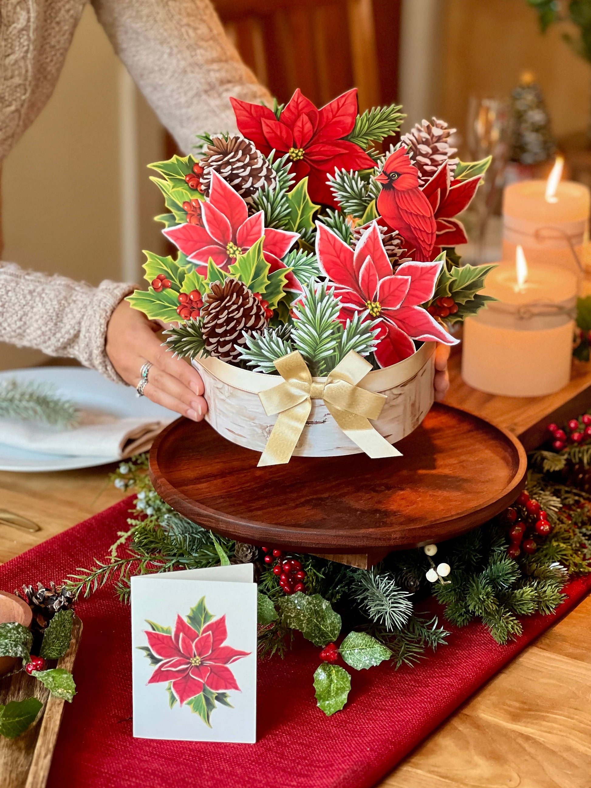 Birch Poinsettia Pop-up Greeting Card from stationery store, featuring poinsettias, pinecones, holly in a birch log with champagne bow