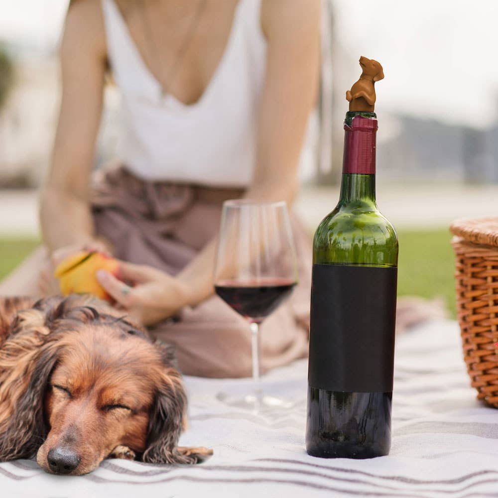 Dachshund bottle stopper on wine at picnic, stationery store item.