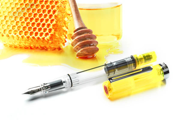 TWSBI ECO Transparent Yellow Fountain Pen with honeycomb background from stationery store, showcasing vibrant design and piston-filling system.