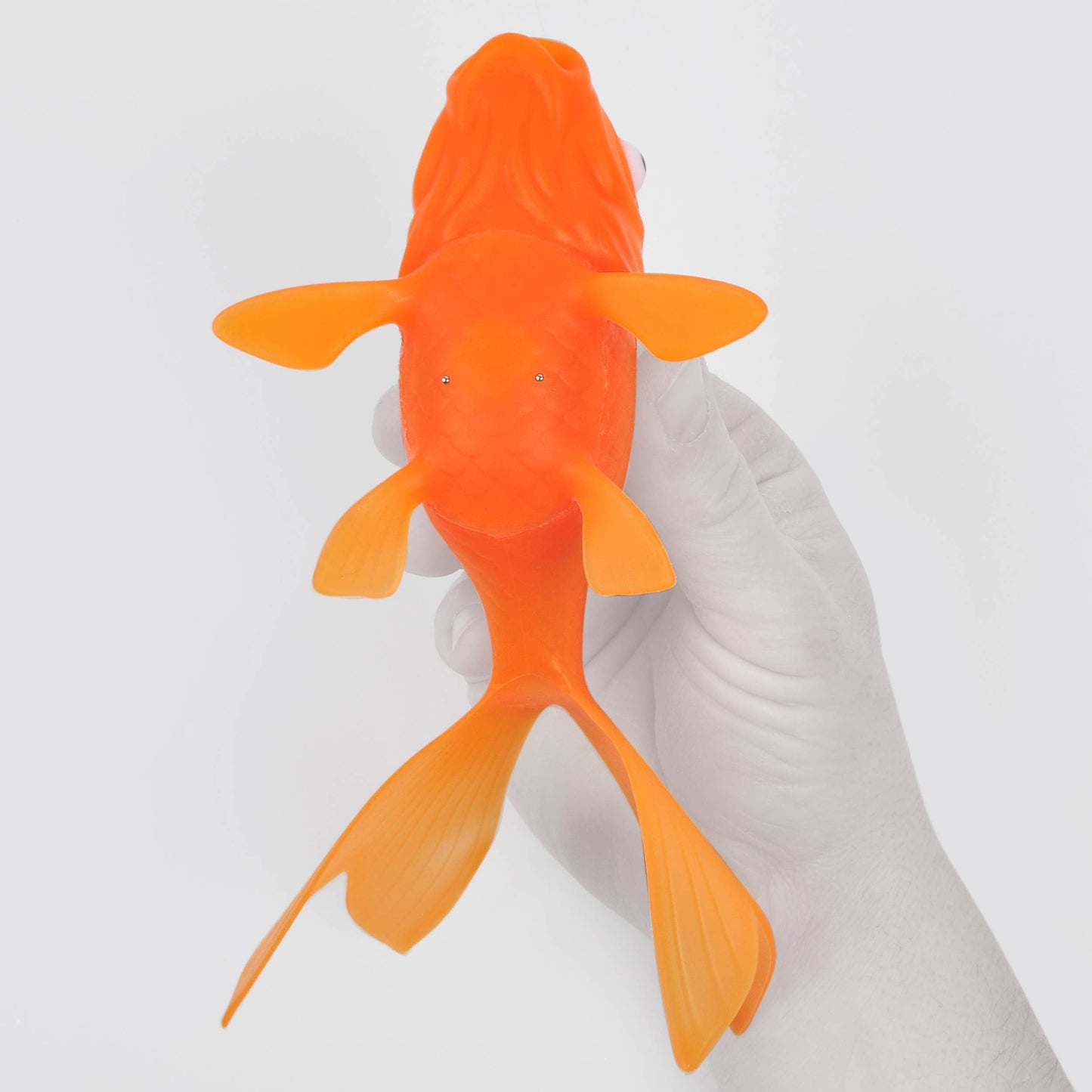 Person holding Koi Toy - Light-Up Goldfish, a vibrant bath and pool toy from stationery store, made of BPA-free silicone, glowing when wet.