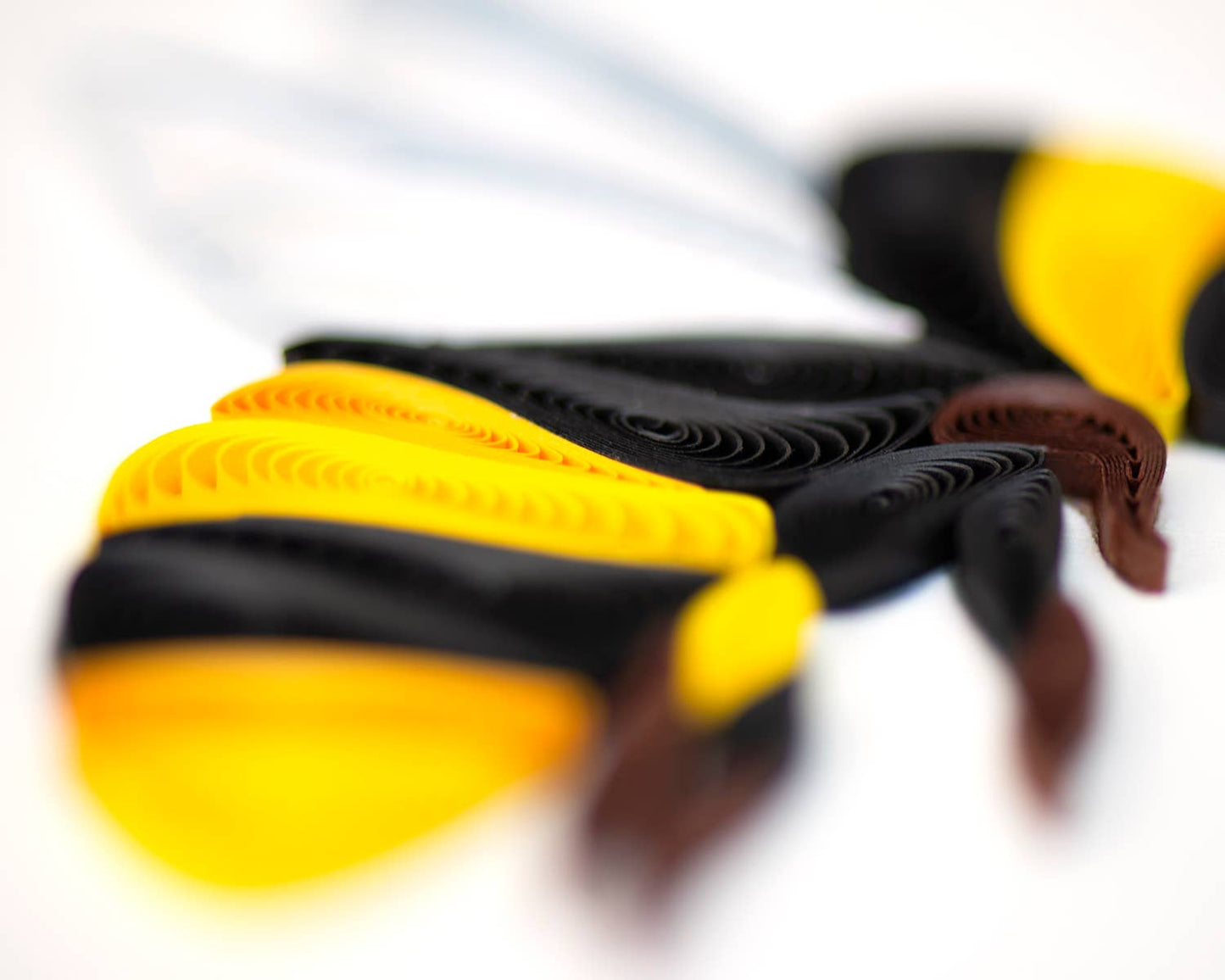 Close-up of handcrafted Bumble Bee card from stationery store, showing intricate black and yellow stripes on quilled bee design.