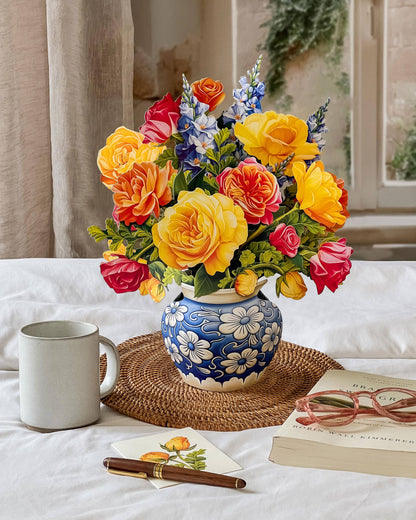 Sorbet Roses Pop Up Greeting Card with bold roses in blue vase, stationery store display.