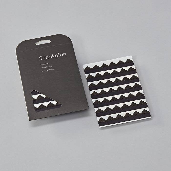 Self-adhesive photo corners in black packaging, ideal for scrapbooks and albums. Available at stationery stores. Size: 0.7 x 0.7 in.