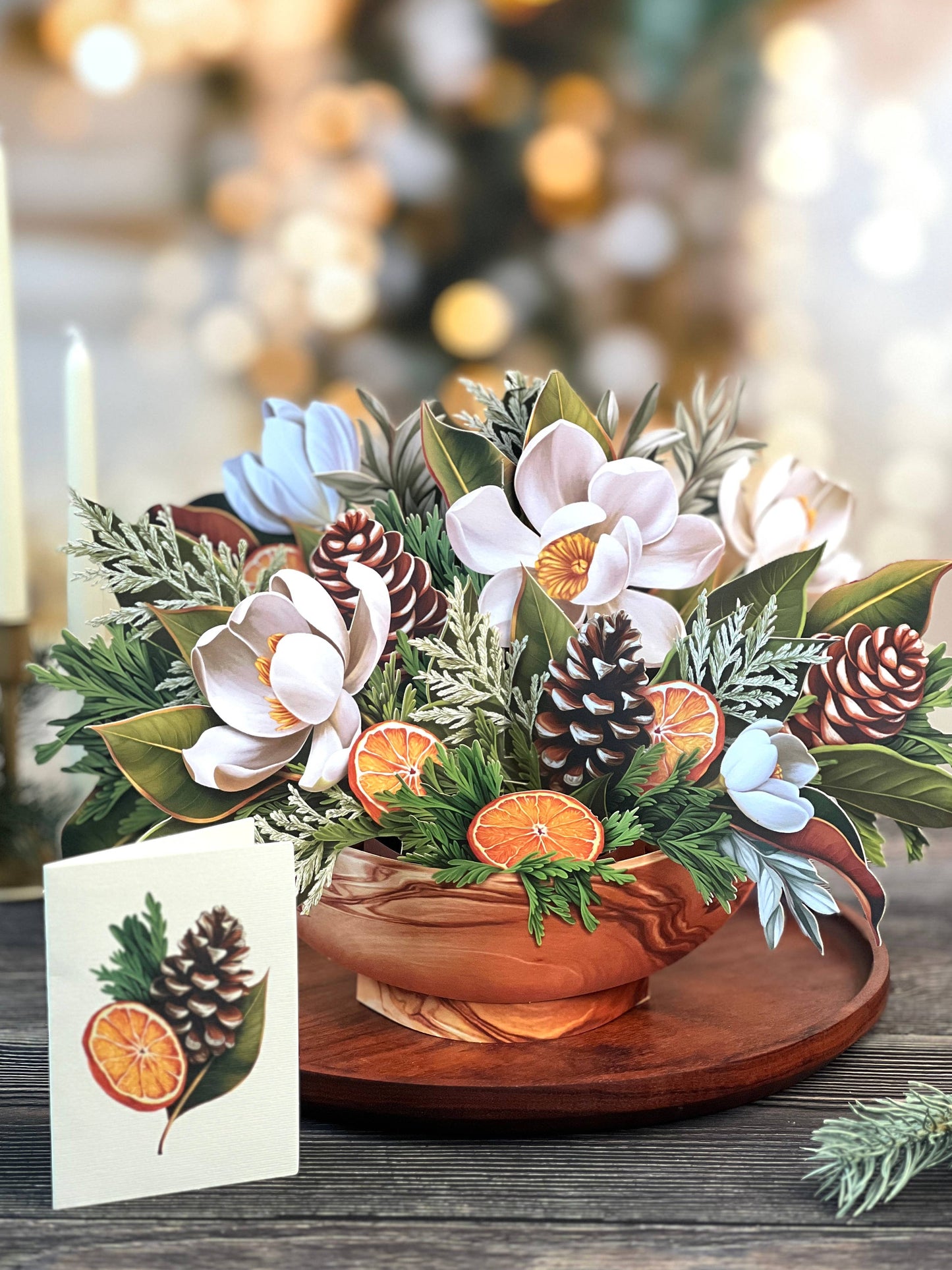 Winter Magnolia Pop-up Greeting Card featuring a bouquet with magnolias, orange slices, and pine cones from a stationery store.