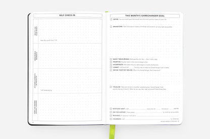 Open pages of a Daily Planner - Undated Cosmic Blue, showing self-check-in and monthly goal sections, available at stationery stores.