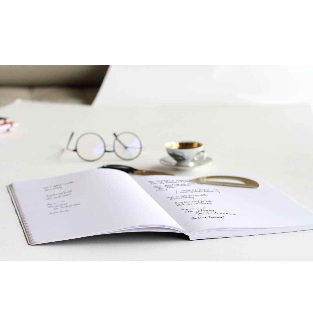 Open Rhodia Composition Book on a desk with glasses and coffee, featuring smooth ultra white paper, available at stationery store.