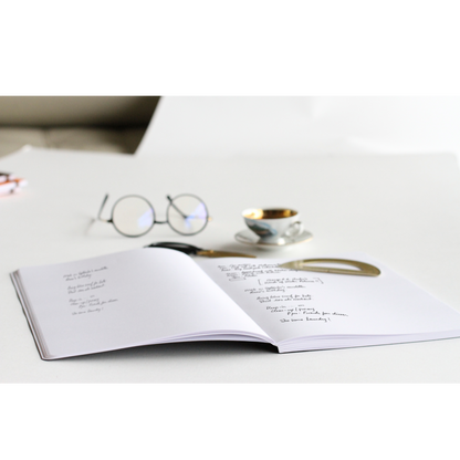 Open Rhodia Composition Book on a desk with glasses and coffee, featuring smooth ultra white paper, available at stationery store.